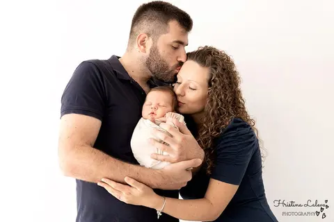 Родителите прегръщат новороденото си, а бащата целува майката по косата